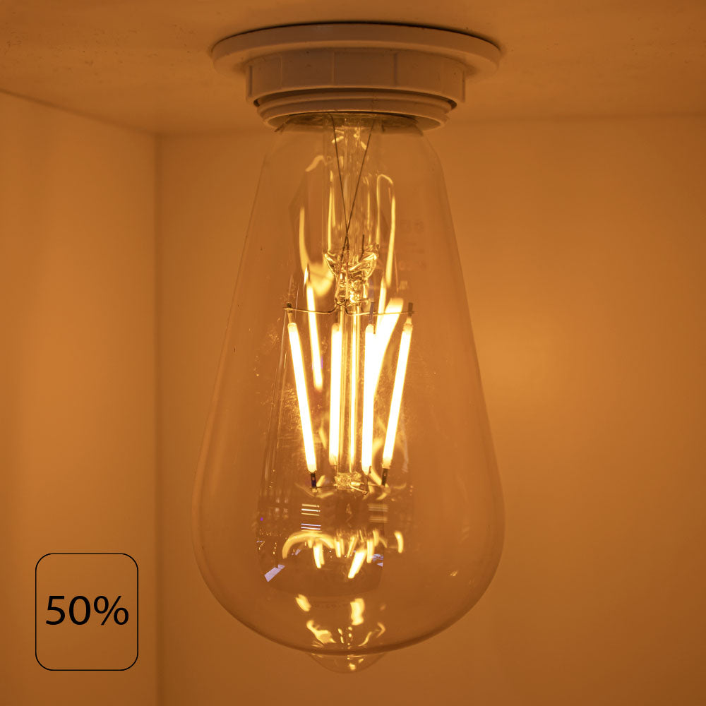 Close-up van een brandende LED filament lamp in peervorm, gemonteerd aan het plafond, met warme gele gloed op 50% lichtsterkte – onderaanzicht.