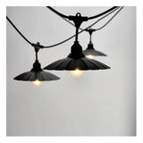 Close-up zijaanzicht van een zwarte outdoor lichtslinger met drie brandende lampen, voorzien van vintage stijl metalen kappen tegen een neutrale achtergrond.