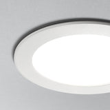 Close-up zijaanzicht van een ronde, witte inbouw LED plafondspot gemonteerd in een lichtgrijs plafond, met strak en modern design en egaal verspreid licht.