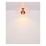 Moderne plafondlamp met glazen kap in koperkleurige afwerking, gezien in vooraanzicht gemonteerd aan een wit plafond, verspreidt warm licht voor een sfeervolle uitstraling.