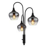 Staande design lamp met drie gebogen armen en rookglas lampenkappen, vooraanzicht met zichtbare gloeilampen in warme lichtkleur.