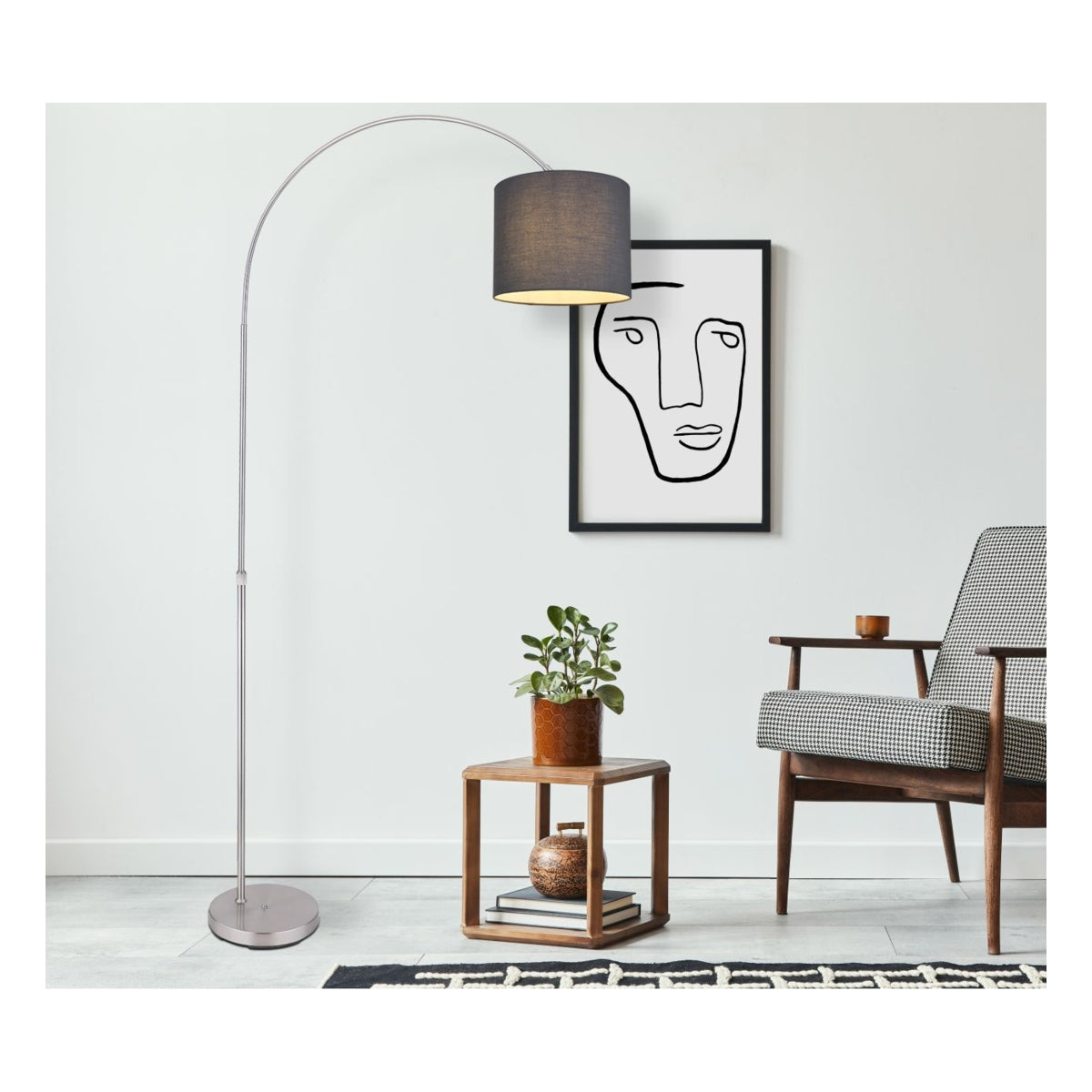 Moderne booglamp met zwarte lampenkap en metalen voet, geplaatst in een stijlvol interieur met een designstoel, houten bijzettafeltje en abstracte wandkunst – vooraanzicht.