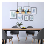 Moderne eettafelset met houten tafelblad, zwarte metalen poten en vier grijze eetkamerstoelen met houten poten, frontaal aanzicht; de set staat in een minimalistisch interieur met botanische wanddecoratie en drie hanglampen.