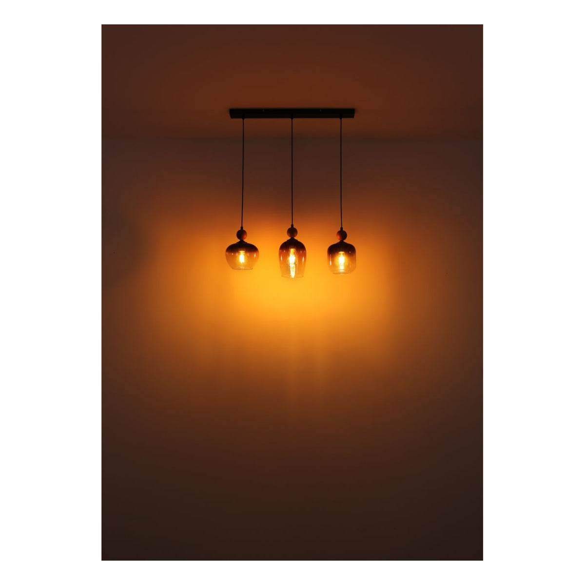 Hanglamp met drie amberkleurige glazen kappen en warm licht, frontaal aanzicht tegen een neutrale muur.