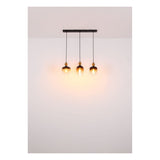 Hanglamp met drie amberkleurige glazen kappen in industriële stijl, gezien vanaf de voorzijde gemonteerd aan het plafond, met warm licht dat tegen een witte muur schijnt.