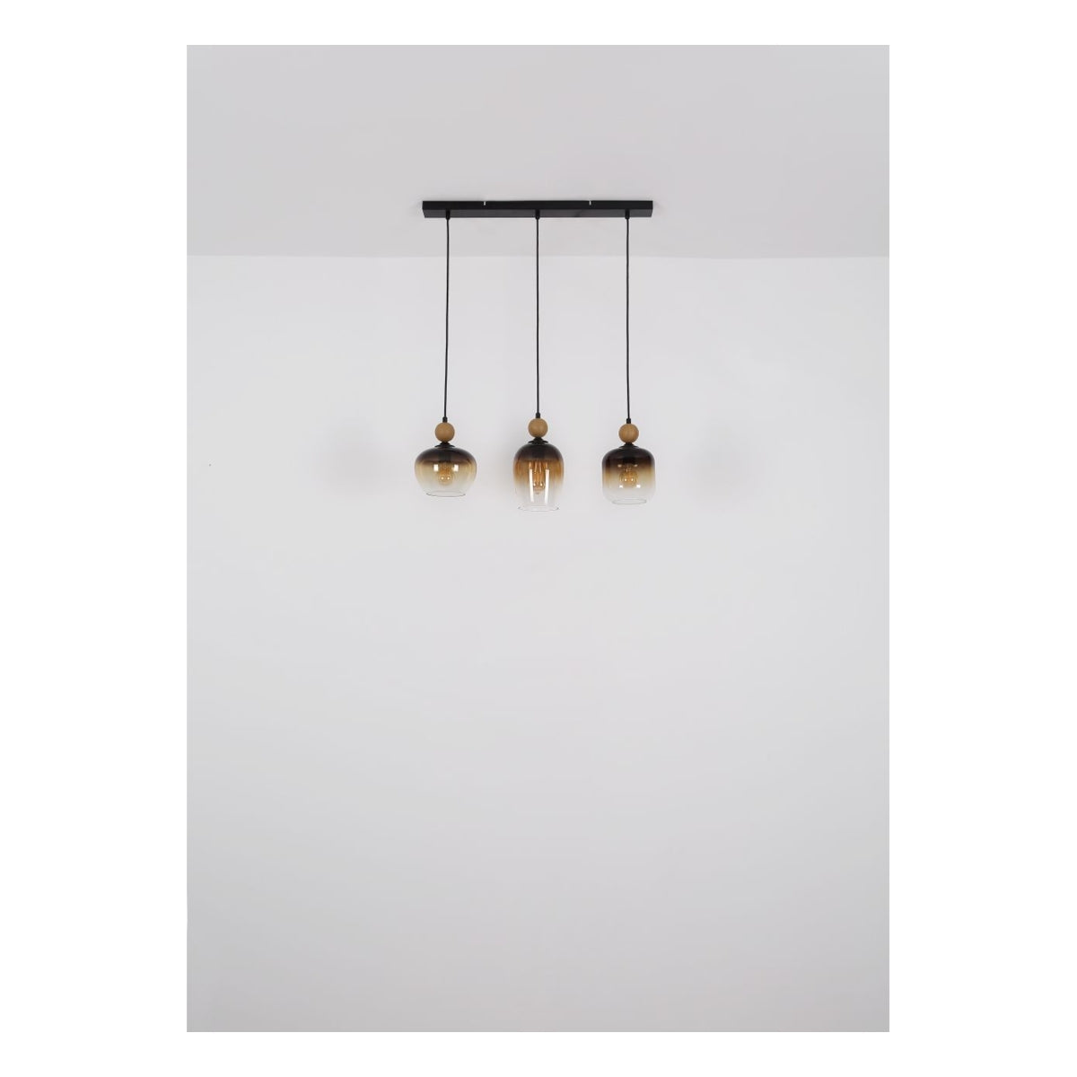Hanglamp Trio Amber Glass – vooraanzicht van moderne hanglamp met drie amberkleurige glazen lampenkappen aan zwarte snoeren, gemonteerd aan een rechthoekige plafondplaat.