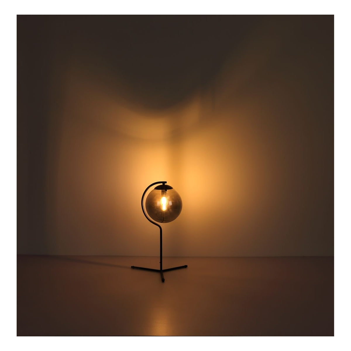 Zijaanzicht van een moderne tafellamp met ronde glazen kap en warm licht, geplaatst tegen een neutrale achtergrond voor een sfeervolle verlichting.