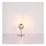 Moderne tafellamp met ronde glazen kap en zwart metalen frame, sfeervol verlicht, vooraanzicht tegen een minimalistische witte achtergrond.