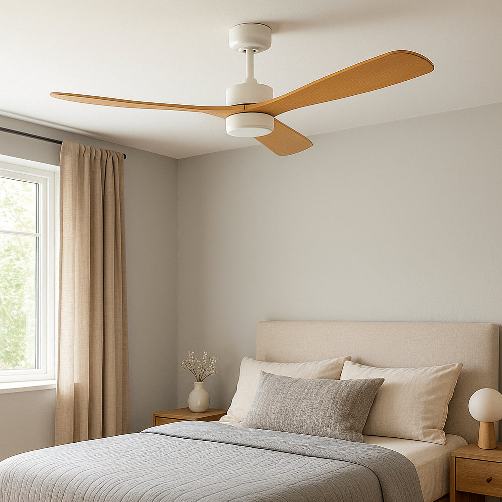 Plafondventilator met houten bladen en witte motorbehuizing, gezien vanuit een frontaal aanzicht in een modern, neutraal ingerichte slaapkamer met natuurlijke lichtinval.