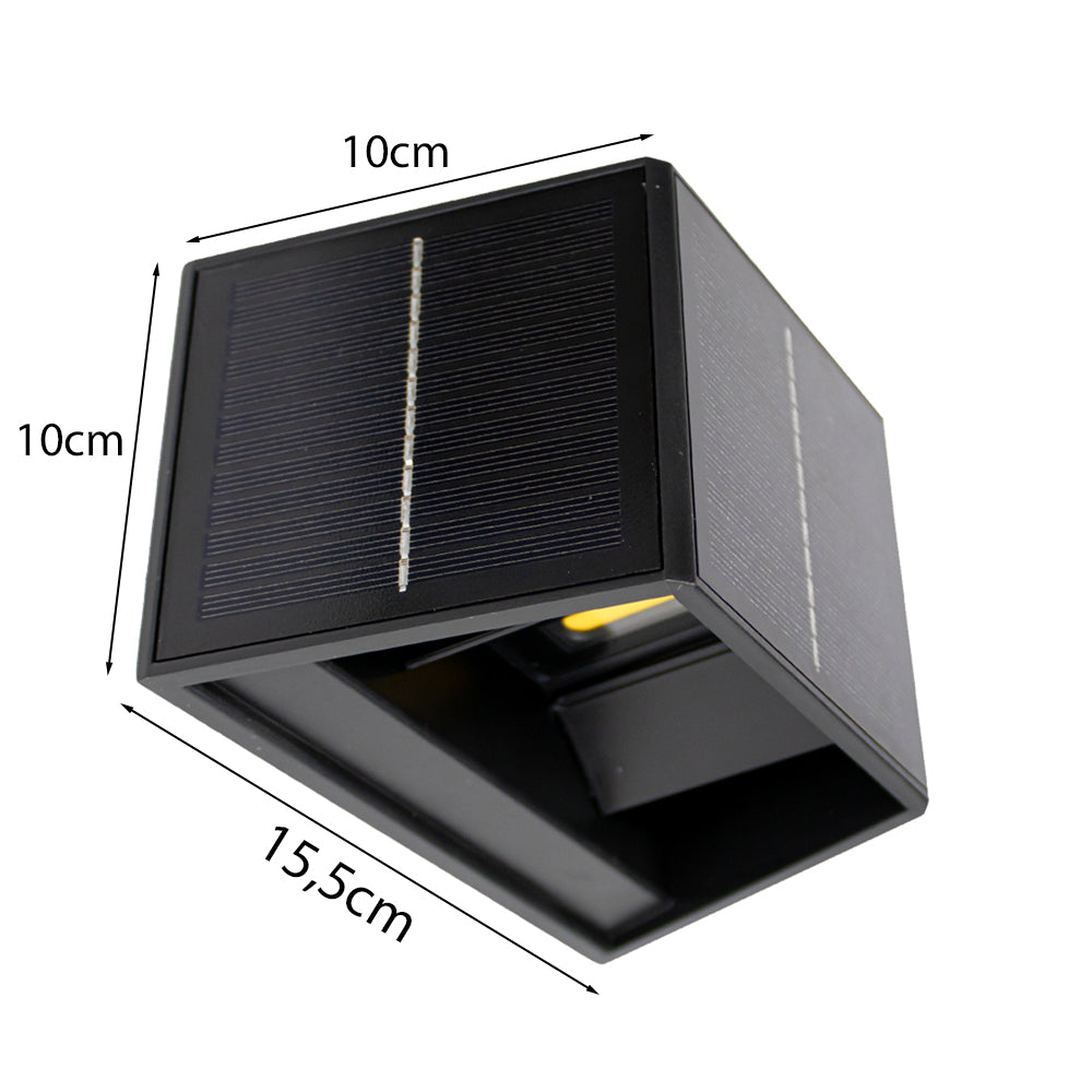 Zwart kubusvormig solar wandlampje met afmetingen 10x10x15,5 cm, schuin vanonder gefotografeerd, met zicht op het zonnepaneel aan de bovenkant en zijkanten.