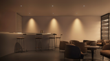Moderne minimalistische barinrichting met hoge barkrukken en ronde loungestoelen, sfeervol verlicht met warm wit licht – vooraanzicht van de bar en zitgedeelte in een luxe horecagelegenheid.