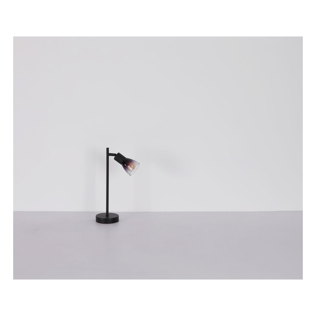 Zwarte moderne bureaulamp met ronde voet en verstelbare glazen kap, zijaanzicht tegen een neutrale achtergrond.