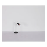 Zwarte moderne bureaulamp met ronde voet en verstelbare glazen kap, zijaanzicht tegen een neutrale achtergrond.