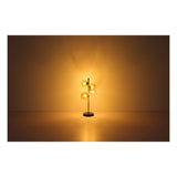 Design tafellamp met vijf amberkleurige glazen bollen, staand op een metalen voet, brandend in een warme sfeerverlichting – frontaal aanzicht tegen neutrale achtergrond.