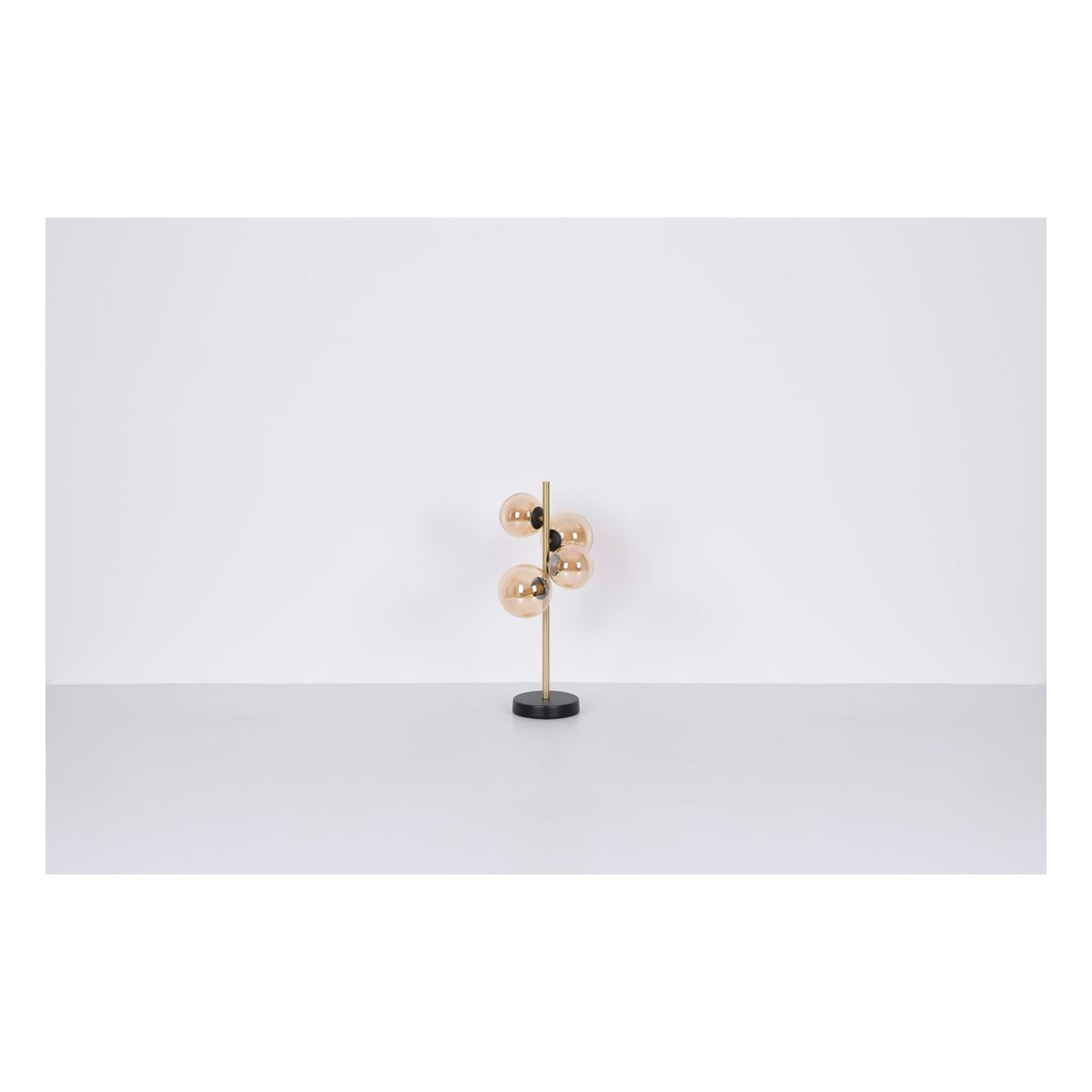 Moderne tafellamp met goudkleurige glazen bollen en messingkleurige staander op zwarte ronde voet, vooraanzicht tegen witte achtergrond.