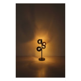 Moderne tafellamp met gouden glazen bollen en zwarte voet, sfeervol verlicht tegen een donkere achtergrond – frontaal aanzicht.