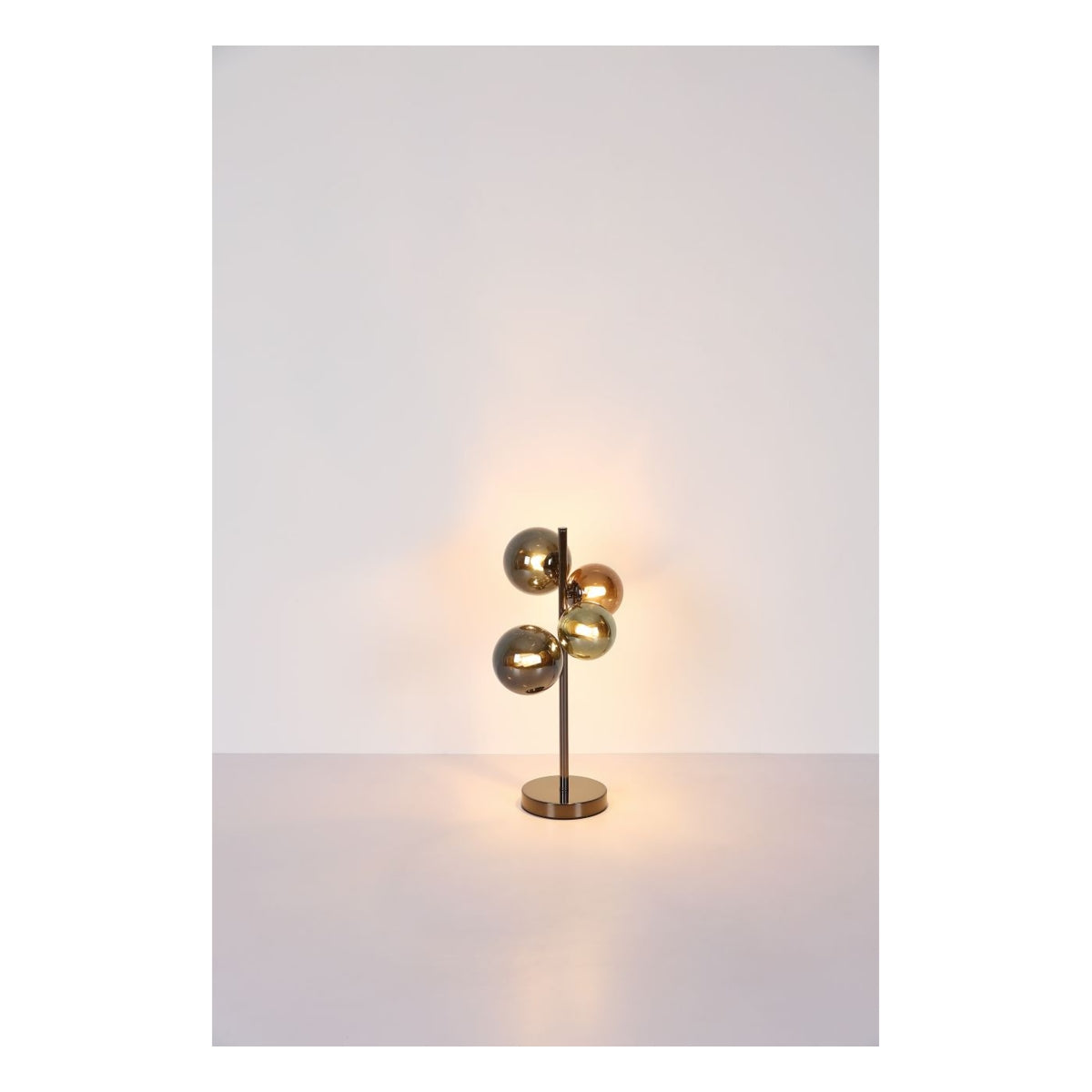 Moderne tafellamp met vier glanzende bolvormige glazen kappen in goudtinten, gemonteerd op een verticale metalen standaard met ronde voet, gefotografeerd in vooraanzicht tegen een neutrale achtergrond.