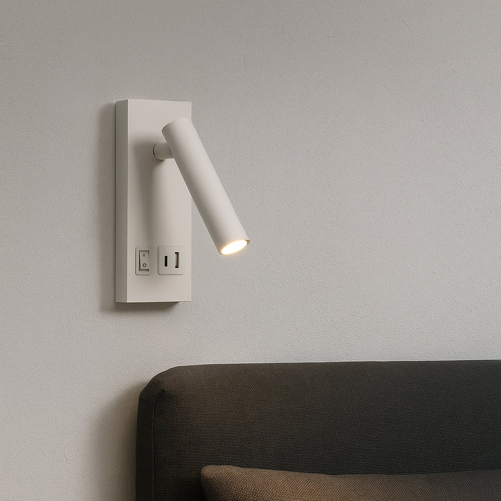 Wandlamp met modern design en geïntegreerde USB- en lichtschakelaar, zijaanzicht van gemonteerd armatuur boven bed tegen een lichte muur, met gerichte cilindervormige leeslamp in witte afwerking.