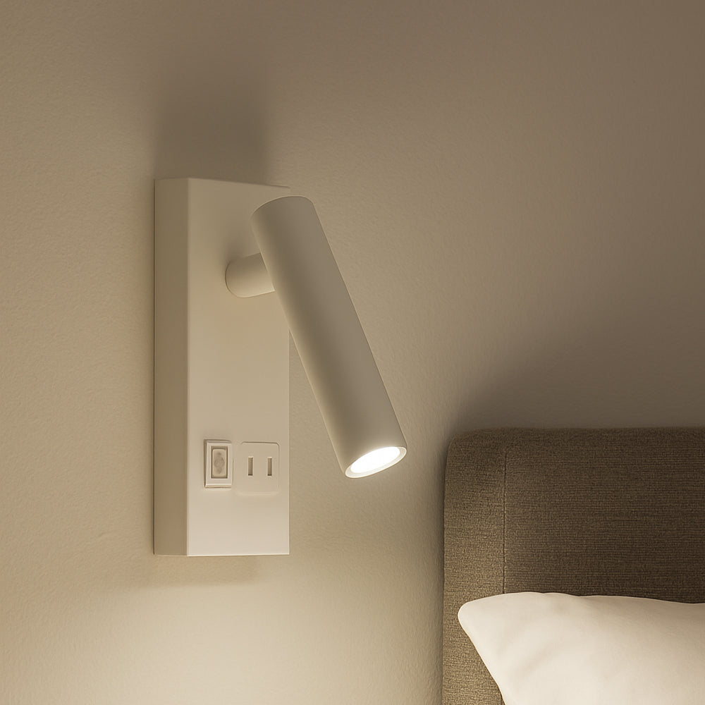 Moderne witte wandlamp met verstelbare cilindervormige leesarm, gemonteerd naast een bed, zijaanzicht in warme sfeerverlichting.