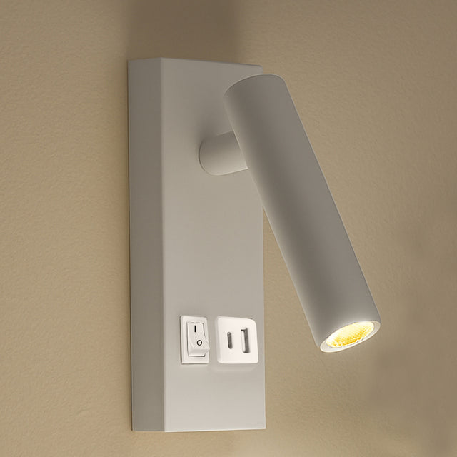 Wandlamp met verstelbare cilindervormige LED-spot in mat wit, inclusief schakelaar en USB-poort – zijaanzicht gemonteerd op een beige muur.
