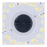 Close-up bovenaanzicht van een ronde LED-lamp met meerdere LED-clusters en een centrale zwarte aansluiting.