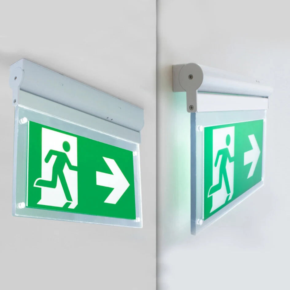 Dubbelzijdig verlichte nooduitgang bewegwijzering met groene achtergrond en witte pictogrammen van een rennend persoon en pijl naar rechts, gemonteerd aan een muurhoek, schuinaanzicht.