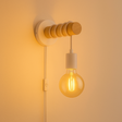 Moderne wandlamp met houten en metalen accenten, zichtbaar vanuit zijaanzicht, met een warm gloeiende filament LED-lamp aan een stoffen snoer en geïntegreerde wandschakelaar.