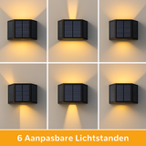 Zwarte solar wandlamp met zes instelbare lichtstanden, aanzicht van voren tegen een muur, toont verschillende warmwitte lichtpatronen voor buitenverlichting.