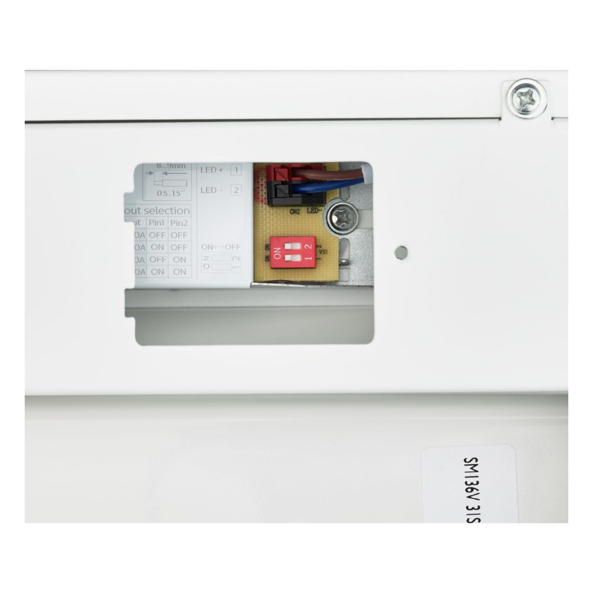 Detailaanzicht van de binnenzijde van een noodverlichtingsarmatuur, met zicht op DIP-switches, bedrading en een instelpaneel voor configuratie.