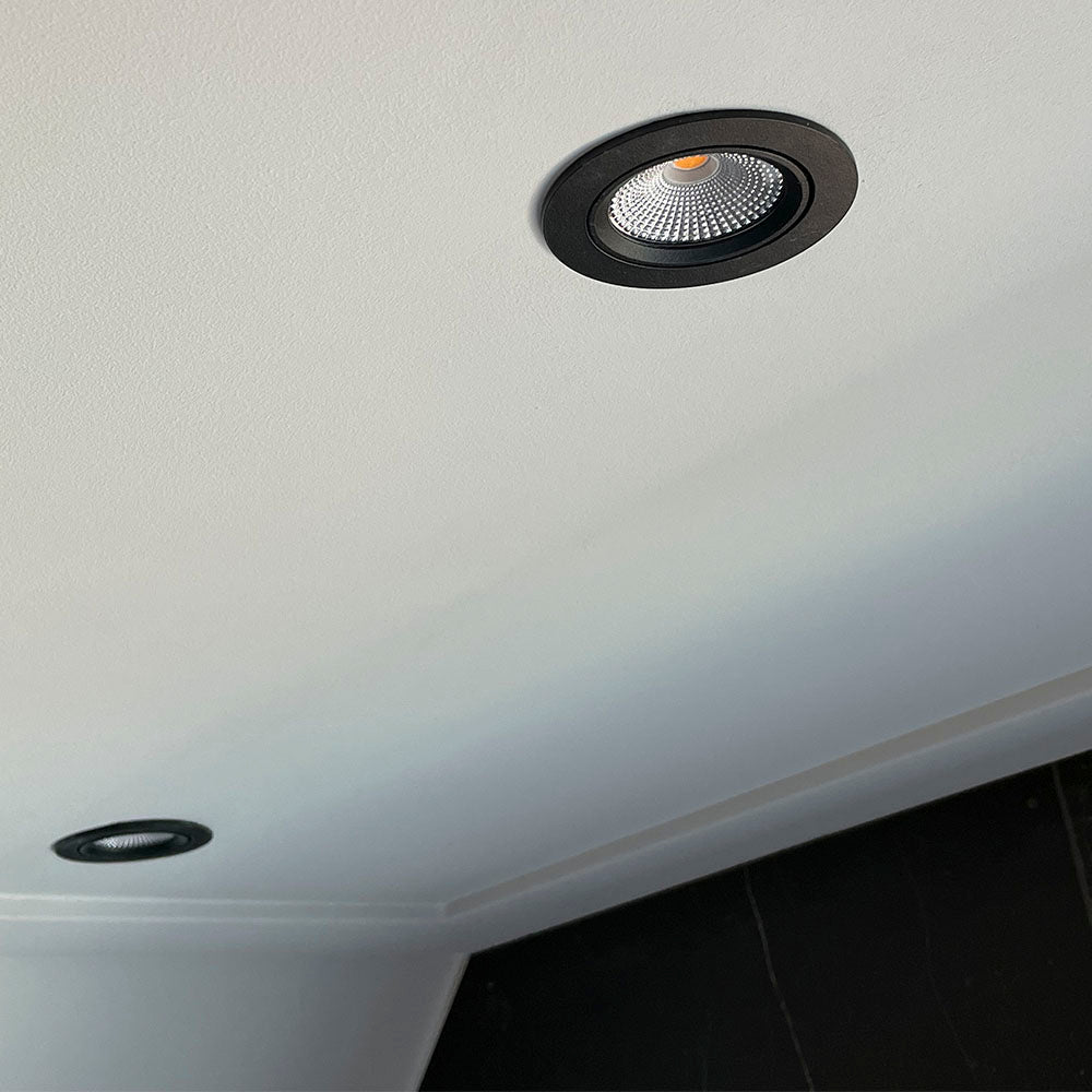Zwarte ronde inbouwspot LED gemonteerd in wit plafond, schuin van onderen gefotografeerd ter illustratie van het design en de afwerking.