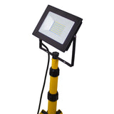 LED bouwlamp op statief, schuin vooraanzicht, met rechthoekige behuizing en gele verstelbare standaard.