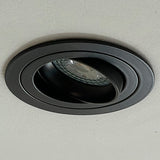 Zwarte ronde verstelbare inbouwspot gemonteerd in plafond, schuin zijaanzicht toont de kantelbare LED-lamp binnenin de armatuur.