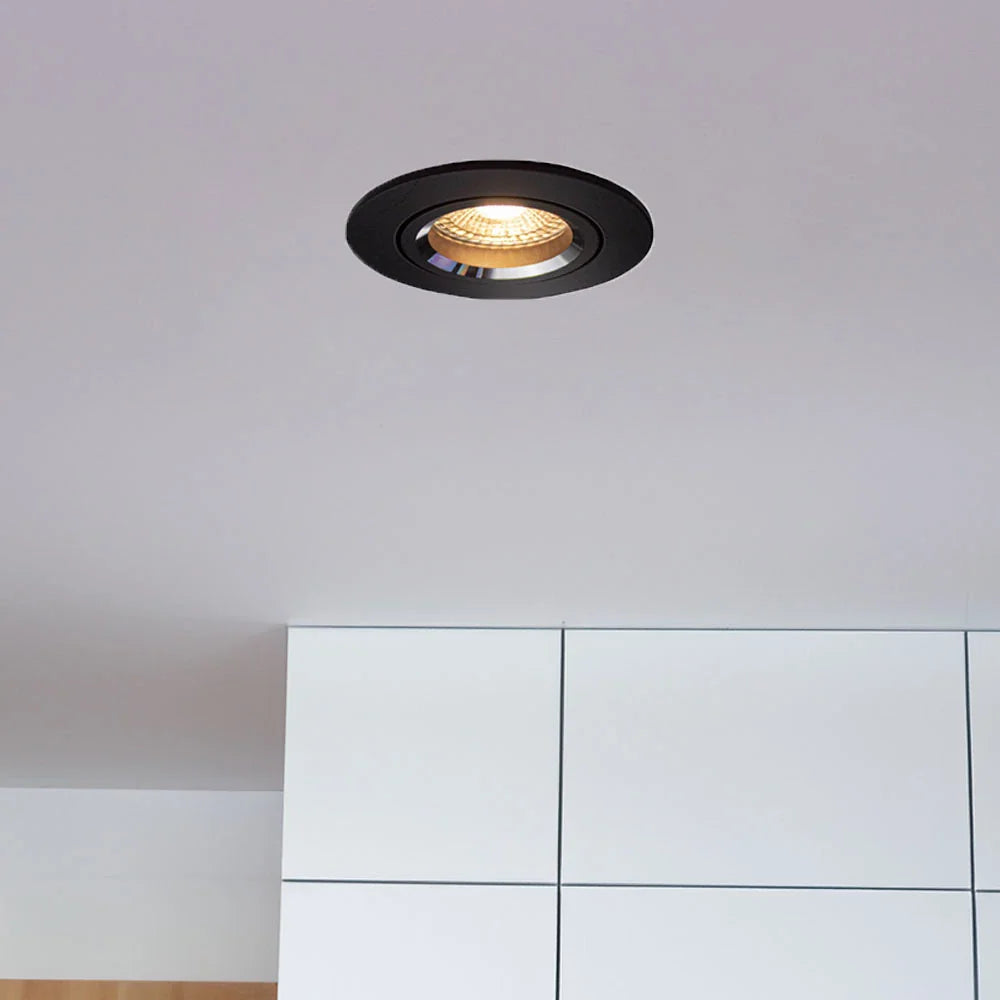Zwarte ronde LED inbouwspot gemonteerd in een wit plafond, gezien vanuit een onderaanzicht in een moderne interieursetting.