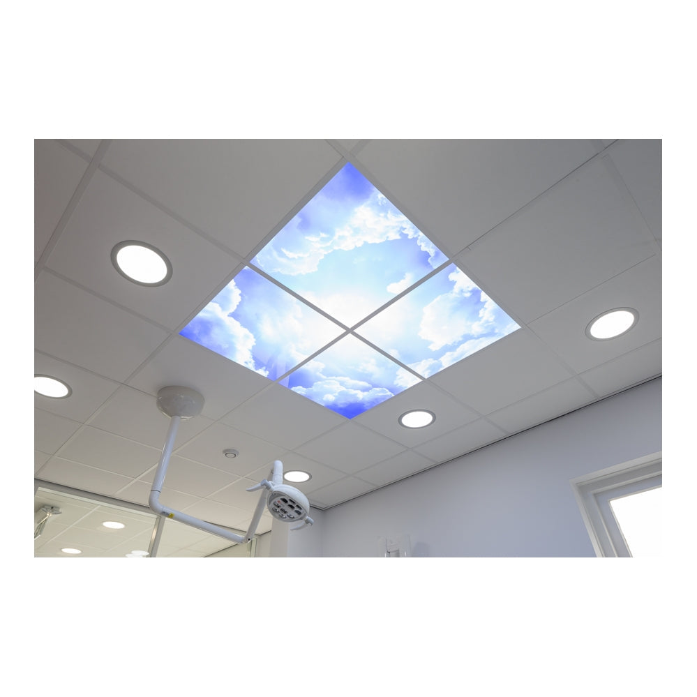 Plafondaanzicht van een verlicht systeemplafond met LED panelen met blauwe lucht en wolkenprint, geïnstalleerd in een moderne behandelruimte of tandartspraktijk.
