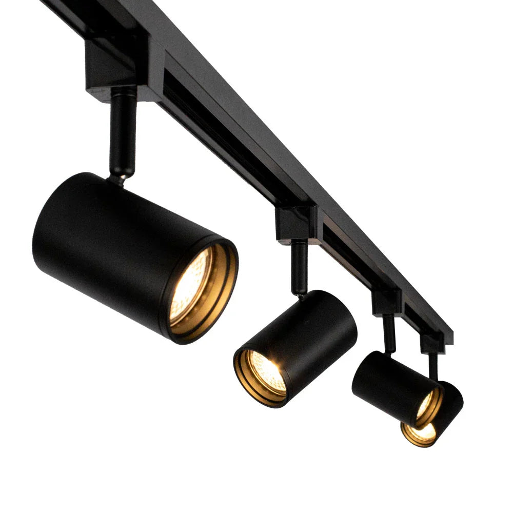 Zwart aluminium railverlichtingssysteem met drie cilindervormige spotlampen, schuin van onderen bekeken tegen een witte achtergrond.
