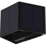 Zwarte kubusvormige solar wandlamp met geïntegreerde zonnepaneelpanelen, schuin van onderen en zijkant gefotografeerd tegen een witte achtergrond.