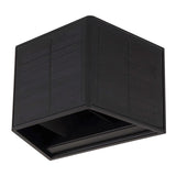 Zwarte solar wandlamp in kubusvorm met geïntegreerd zonnepaneel, schuin vanonder in hoekaanzicht gefotografeerd tegen een witte achtergrond.