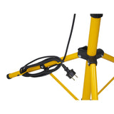 Detailaanzicht van de onderzijde van een gele statiefconstructie met stroomkabel en stekker, waarschijnlijk behorend bij een bouwlamp of werklamp op statief, gefotografeerd vanuit een zijhoek.