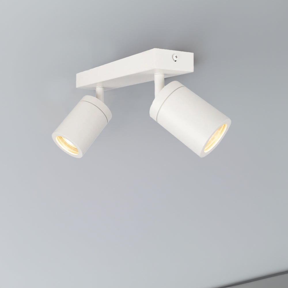 Witte moderne plafondlamp met twee verstelbare spots, gemonteerd tegen een lichtgrijs plafond, schuin van onderen gefotografeerd.