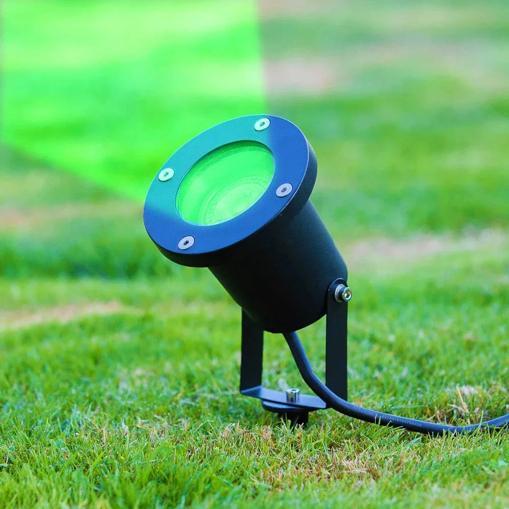Zwarte LED buitenstraler met groene lichtbundel, zijaanzicht op grasveld, ideaal voor tuinverlichting of accentverlichting.