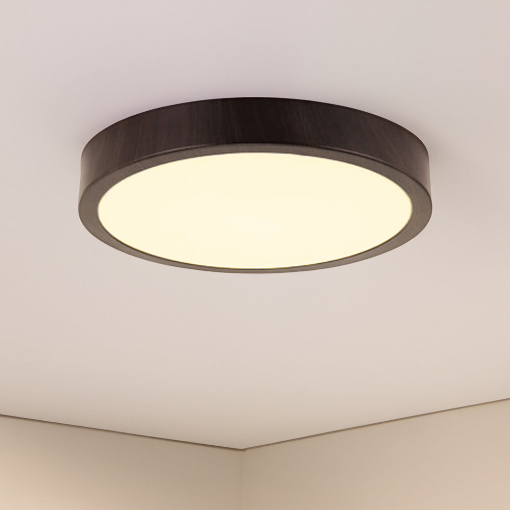 Moderne ronde plafondlamp met donkerhouten rand en diffuus wit licht, onderaanzicht tegen een wit plafond.