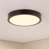 Moderne ronde plafondlamp met donkerhouten rand en diffuus wit licht, onderaanzicht tegen een wit plafond.