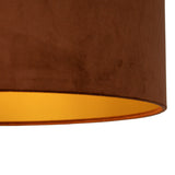 Close-up zijaanzicht van een ronde, bruine velvet lampenkap met een goudkleurige binnenkant.