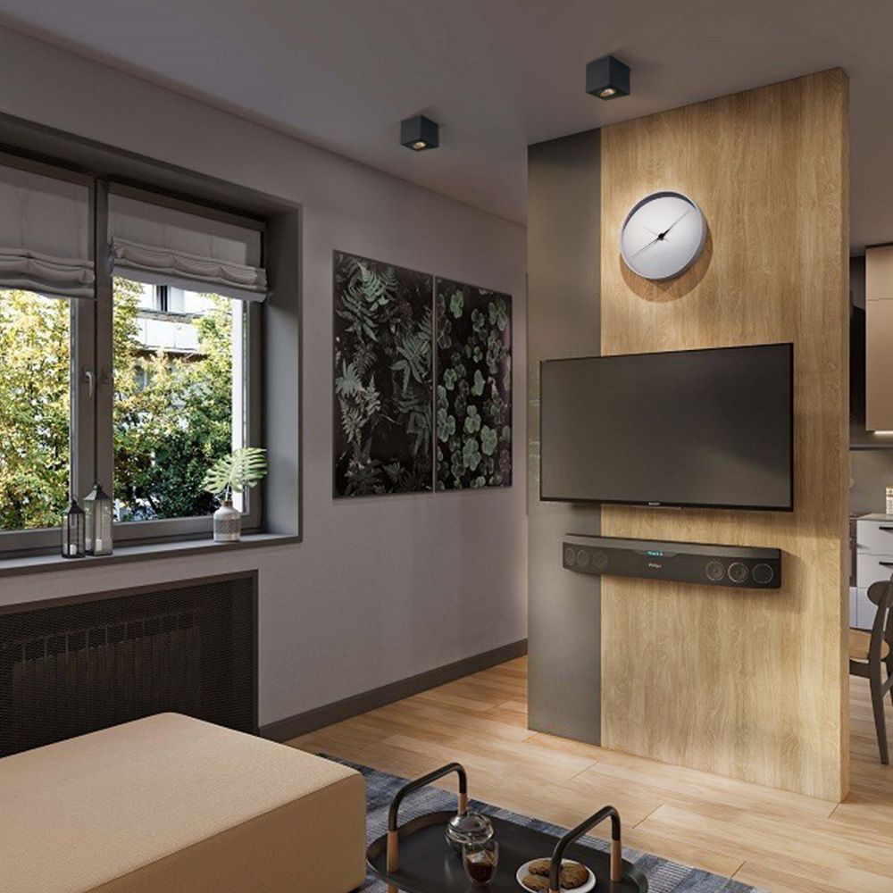 Moderne woonkamer met een wandgemonteerde flatscreen tv en Philips Fidelio B97 soundbar aan een houten accentmuur, frontaal aanzicht met sfeervolle verlichting en decoratieve elementen zoals een klok, planten, en kunst aan de muur.