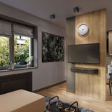 Moderne woonkamer met een wandgemonteerde flatscreen tv en Philips Fidelio B97 soundbar aan een houten accentmuur, frontaal aanzicht met sfeervolle verlichting en decoratieve elementen zoals een klok, planten, en kunst aan de muur.