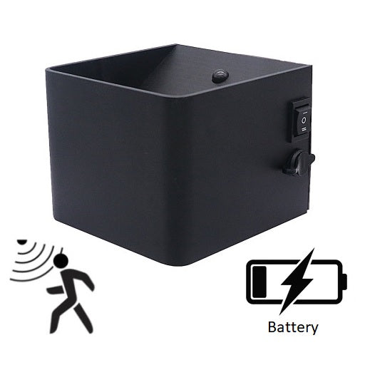 Zwarte vierkante wandlamp met bewegingssensor en batterijvoeding, schuin vooraanzicht met zicht op aan/uit schakelaar en instelknop aan de zijkant.