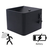 Zwarte vierkante wandlamp met bewegingssensor en batterijvoeding, schuin vooraanzicht met zicht op aan/uit schakelaar en instelknop aan de zijkant.