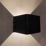 Moderne zwarte wandlamp met op- en neerwaarts licht, gemonteerd op een gestructureerde witte muur – zijaanzicht.