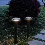 Twee moderne zwarte tuinpalen met ronde LED-verlichting, geplaatst langs een tuinpad in een avondsetting – frontaal aanzicht.
