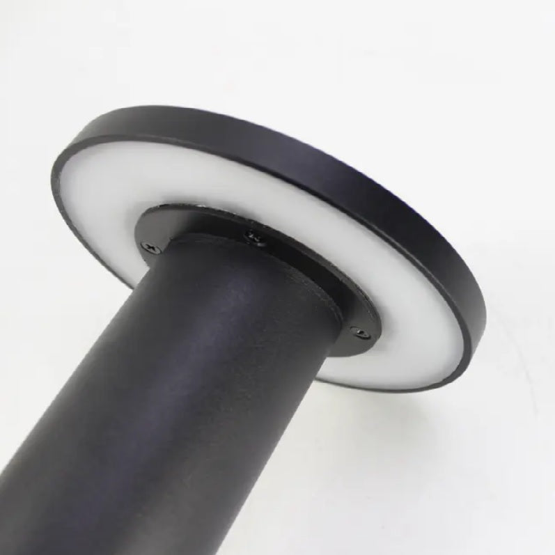 Detailaanzicht van een moderne zwarte buitensokkelarmatuur met ronde LED-lichtkop en matwitte diffuser, weergegeven vanuit een schuine onderaanzicht.